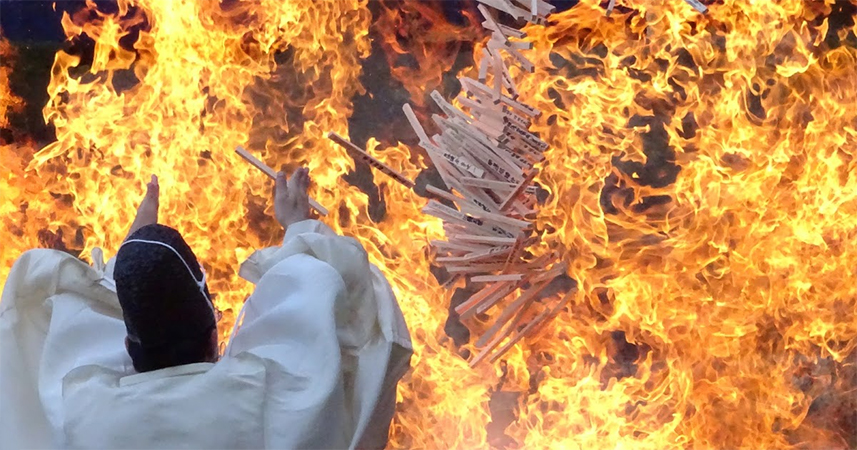 Shinto priest throwing goma sticks onto an enormous bon fire